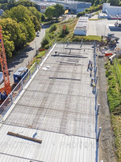 Workers on construction site with crane in sunny weather, surrounded by roads and fences, car park construction, Calw, Germany