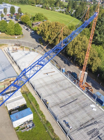 View from above of a construction site with a blue crane and construction workers, surrounded by trees, car park construction, Calw, Germany