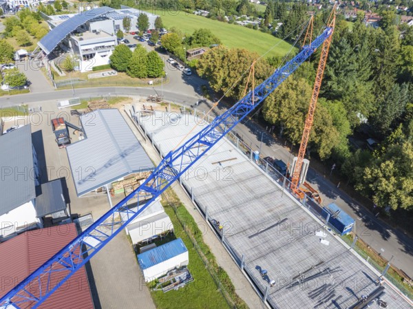 Large crane over construction site during building work in green surroundings with roads, car park construction, Calw, Germany