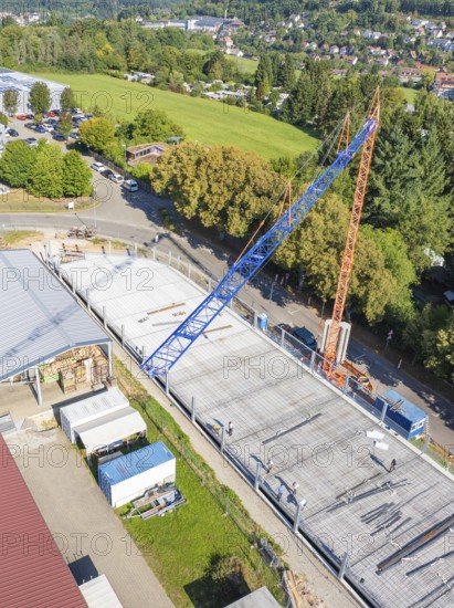 Aerial view of a construction site with crane and partially constructed building surrounded by trees, car park construction, Calw, Germany