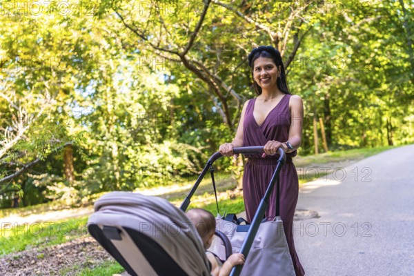Latin mother enjoying a sunny summer day while walking in the park with her baby in a stroller, surrounded by lush greenery and cheerful vibes