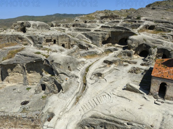 Ancient cave town with weathered sandstone structures and old paths under a blue sky, aerial view, cave town Uplistsikhe, Uplistsikhe, Inner Kartlia region, Shida Kartli, Georgia