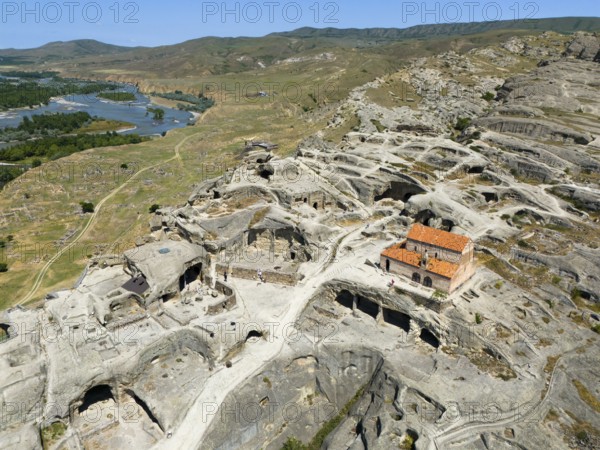 Ruins of the ancient cave city of Uplistsikhe overlooking a wide river and hilly landscape, aerial view, cave city Uplistsikhe, Uplistsikhe, river Kura or Mtkvari, Inner Kartlia region, Shida Kartli, Georgia