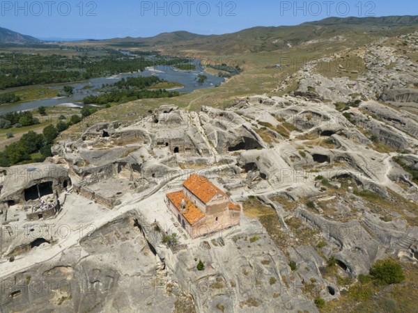 Lonely ancient ruins of Uplistsikhe with orange-coloured roof in the middle of a vast landscape, aerial view, cave city Uplistsikhe, Uplistsikhe, river Kura or Mtkvari, Inner Kartlia region, Shida Kartli, Georgia