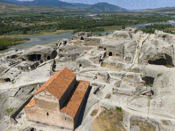 Older sandstone church in a rocky and green valley landscape by the river, aerial view, Princes' Church, cave town Uplistsikhe, Uplistsikhe, river Kura or Mtkvari, Inner Kartlia region, Shida Kartli, Georgia