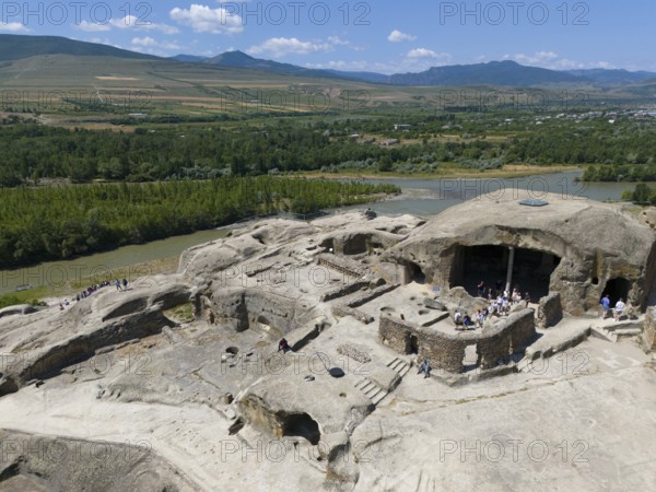 Ancient ruins with tourist visitors, surrounded by river landscapes and mountains, aerial view, cave town Uplistsikhe, Uplistsikhe, river Kura or Mtkvari, Inner Kartlia region, Shida Kartli, Georgia