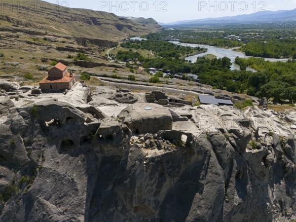 Historic church on rocky cliff with panoramic view of river and green landscape, aerial view, cave town Uplistsikhe, Uplistsikhe, river Kura or Mtkvari, Inner Kartlia region, Shida Kartli, Georgia