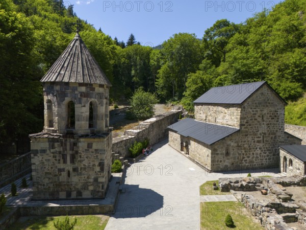 Stone chapel with adjoining buildings in a forest landscape under a clear blue sky, aerial view, Chitakhevi Church of St George, The Green Monastery, Mtsvane Monastery, Samtskhe-Javakheti region, Georgia