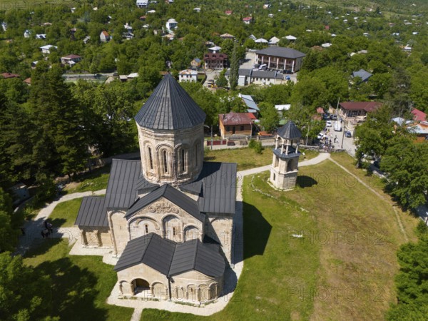 Aerial view of a church with surrounding buildings and green vegetation in a village, aerial view, Nikorzminda Cathedral, Nikorzminda Cathedral, Racha-Lechkhumi region, Lower Svaneti, Georgia