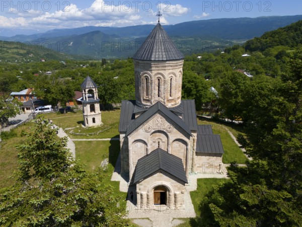 Historic church in a green mountain landscape under a blue sky with clouds, aerial view, Nikorzminda Cathedral, Nikorzminda Cathedral, Racha-Lechkhumi region, Lower Svaneti, Georgia