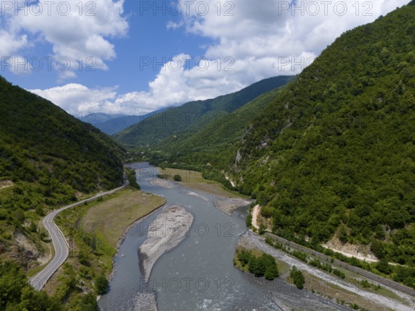 A river flows through a mountainous valley along a winding country road, aerial view, Tskhenitskhali River, Tskhenitskhali, Tsageri, Racha-Lechkhumi region and Lower Svaneti, Georgia