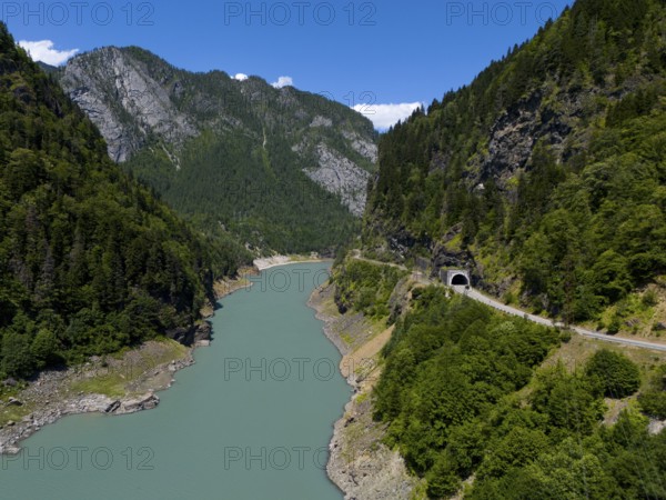 A turquoise-coloured river flows through a wooded valley with mountains and a tunnel in the sunlight, aerial view, Enguri River near Idliani, Samegrelo-Zemo Svaneti province, Svaneti, Georgia