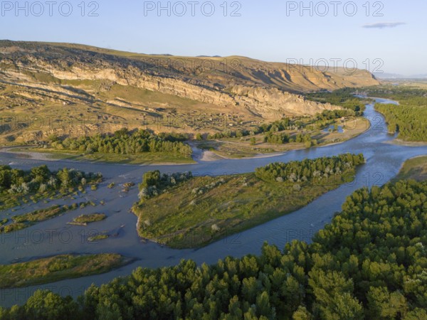 Extensive river landscape with green islands and rocky cliffs, framed by forest areas under a clear sky, aerial view, River Kura or Mtkvari, near Uplistsikhe, Uplistsikhe, Inner Kartlia region, Shida Kartli, Georgia
