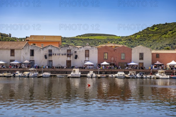 Sardinia, boats in the river Temo and residential buildings on the promenade, guests at the restaurants with outdoor catering, Bosa, Europe, province of Oristano, Italy, architecture, atmosphere, outdoor area, outdoor catering, boats, relaxation, food, river Temo, riverbank, leisure, building, guests, sky, culture, midday, afternoon, promenade, travel, restaurants, shade, sightseeing, seating, summer, city, tourism, tourists, drinking, urban, holiday, water, residential, European, historic, picturesque, Mediterranean, sunny
