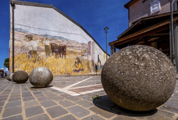 Sardinia, stone balls in front of a house with mural (Murales) Sardinia sight, Tinnura, Europe, Province of Oristano, Italy, architecture, attraction, outdoor, design, detail, village, heritage, facade, open-air, building, house, culture, art, artist, murals, travel photography, destinations, sight, sightseeing, stone, stone balls, street view, symbolism, tourism, mural, brick, colourful, decoration, inviting, unique, European, historical, creative, cultural, artistic, rural, picturesque, Mediterranean, regional, traditional, public art