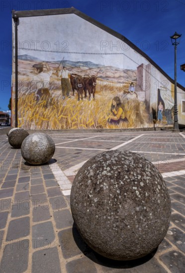 Sardinia, stone balls in front of a house with mural (Murales) Sardinia sight, Tinnura, Europe, Province of Oristano, Italy, architecture, exterior, detail, village, colours, facade, design, house, culture, art, artwork, wall, murals, travel photography, sight, sightseeing, summer, stone balls, structure, symbolism, tourism, tradition, mural, decoration, historical, italian culture, creative, rural, picturesque, mediterranean, mediterranean architecture, mediterranean landscape, regional, visual arts