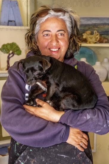 Sardinia, Pina Monne, woman portrait and dog on arm, artist, Tinnura, Europe, Oristano province, Italy, poor, atmosphere, expression, character, emotion, adult, woman, woman portrait, face, pet, dog, identity, interior, inspiration, interaction, creativity, culture, art, artist, landscape, painting, human, personality, portrait, region, sightseeing, city, animal, tourism, European, Italian, stylised, traditional, female