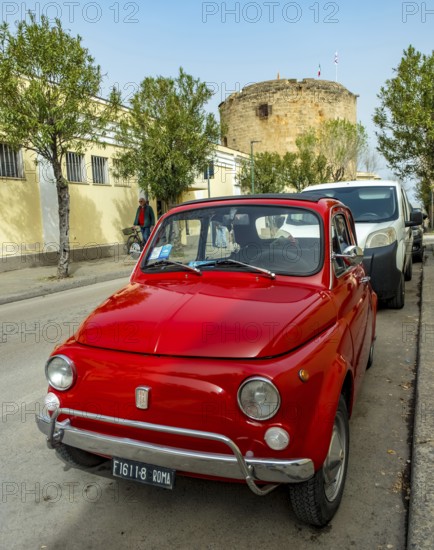 Sardinia, Red Fiat 500 in a street, number plate Roma F1, Alghero, Europe, Province of Sassari, Italy, old town, architecture, car, driving, cars, driving culture, vehicle, Fiat 500, building, small car, number plate, travel, destinations, Roma F1, sight, sightseeing, summer, city, cityscape, street, daytime, tourism, means of transport, urban, holiday, abroad, European, Italian, Mediterranean, red