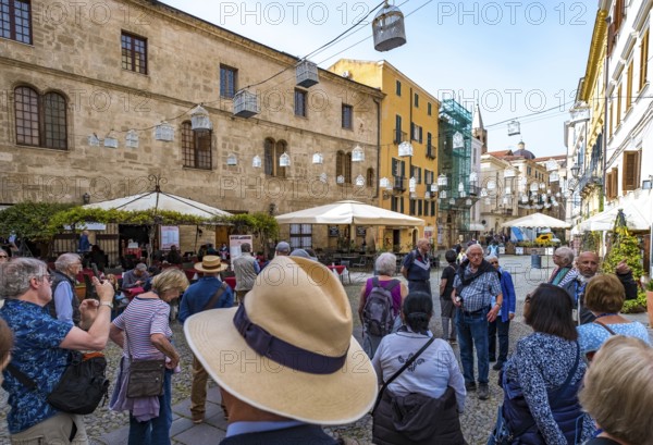 Sardinia, tourist tour group in the old town with sandstone-coloured palazzi, birdcage from house to house over the street, Alghero, Europe, Province of Sassari, Italy, lighting, IT, travel, destination, Ristorante Pizzeria Forno A Legna, sightseeing, tourism, tourist, tourist attraction, tourist trip, birdcage, tourist destination