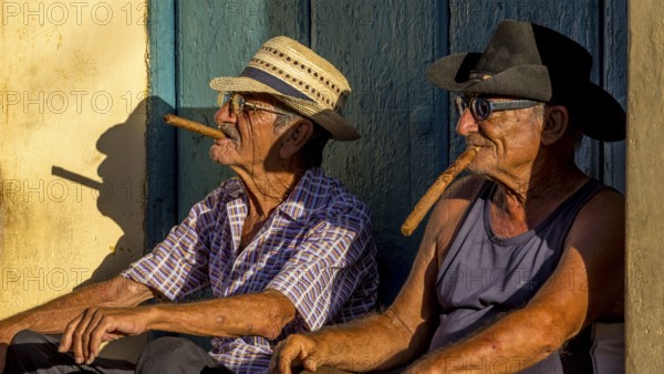 Two old Cubans smoking cigars and sitting on a staircase in the warm light of the sunset, Trinidad, Cuba, Sancti Spíritus, Sancti Spíritus