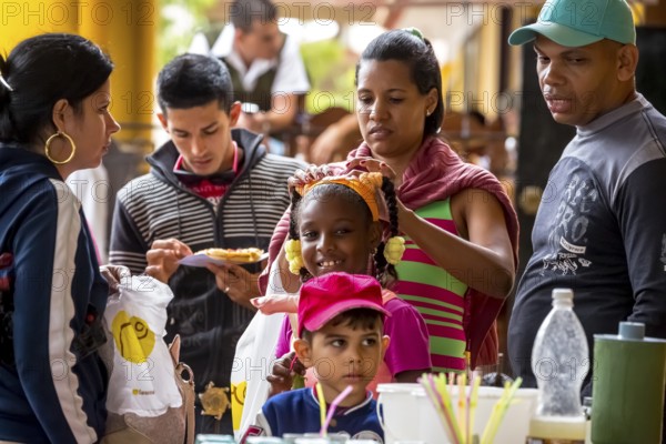 Young girl with pinned-up pigtails at a Cuban pizza stand with her family, Viñales, Cuba, Pinar del Río, Viñales, Pinar del Río
