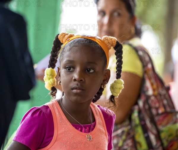 Young girl with pinned-up pigtails at a Cuban pizza stand with her family, Viñales, Cuba, Pinar del Río, Viñales, Pinar del Río