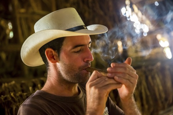 Tobacco farmer, tobacco farmer Luis Manne Alvares Rodrigues lights a Havana cigar, tobacco farm in the Vinales Valley, Viñales, Cuba, Pinar del Río, Viñales, Pinar del Río
