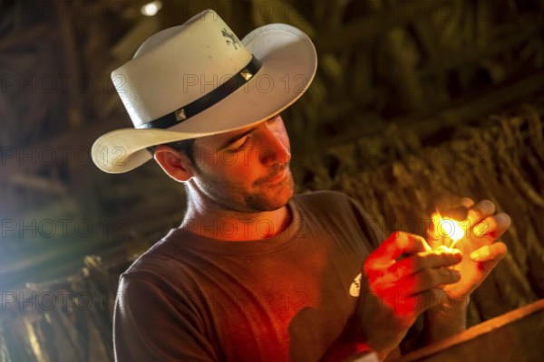 Tobacco farmer, tobacco farmer Luis Manne Alvares Rodrigues lights a Havana cigar, tobacco farm in the Vinales Valley, Viñales, Cuba, Pinar del Río, Viñales, Pinar del Río
