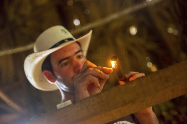 Tobacco farmer, tobacco farmer Luis Manne Alvares Rodrigues lights a Havana cigar, tobacco farm in the Vinales Valley, Viñales, Cuba, Pinar del Río, Viñales, Pinar del Río