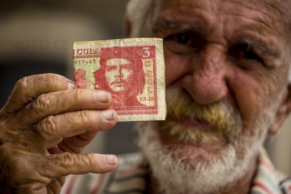 Old Cuban man holding a three peso banknote with the portrait of Ernesto Che Guevara in his hand, local currency, CUP, Cuban Peso, poverty, La Habana, Havana, Cuba, Cuba, Europe, aerial view, birds-eyes view, aerial photography, aerial photography, overview, bird's eye view