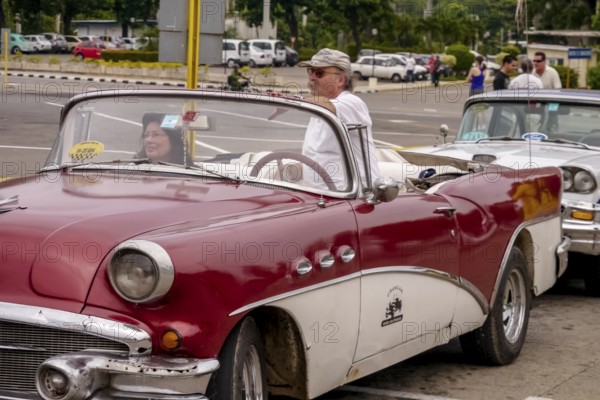 Tourists in a red convertible, red vintage convertible in the street scene, old American road cruisers on the streets of Havana, taxi, Havana, Cuba, Europe, aerial view, birds-eyes view, aerial photography, aerial photography, overview, bird's eye view