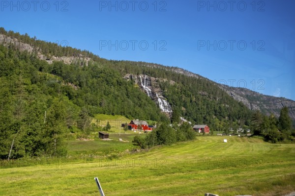 Red mountain huts, meadows, trees, waterfall, mountains, blue sky, Skulestadmo, Hordaland, Norway, Scandinavia, Europe, NOR, travel, tourism, destination, sightseeing, sea voyage, Hurtigruten, Hurtigruten trip, tourism, Norwegian, Scandinavian, tourist, cruise, adventure trip, landscape, forest, forestry, agriculture, water, valley, valley