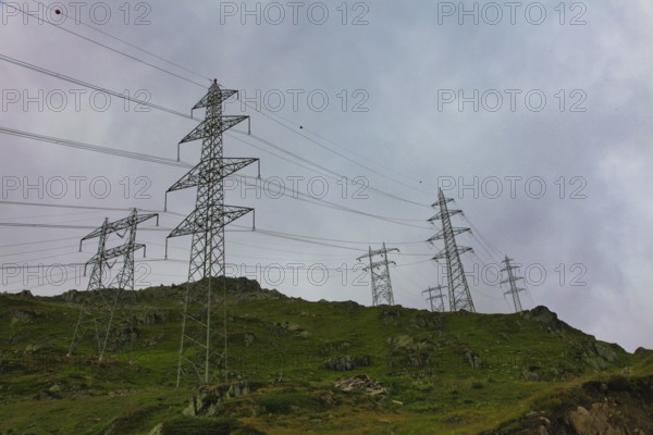 Electricity pylons on an overgrown hill under a cloudy sky, embedded in a natural landscape, power line, mountains, energy, Oberwald, Canton Valais, Switzerland