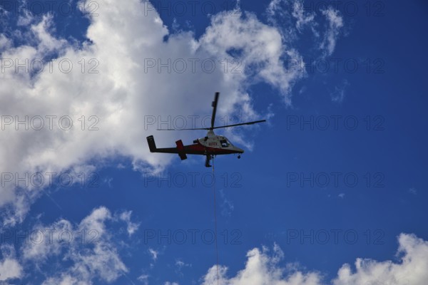 Small helicopter in the blue sky with few clouds, transport helicopter, timber transport, Saas Grund, Canton Valais, Switzerland