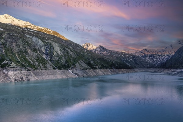 Early morning light over a lake with snow-covered mountains and pink sky, Mattmark reservoir, Saas Almagell, Saas Grund, Canton Valais, Switzerland