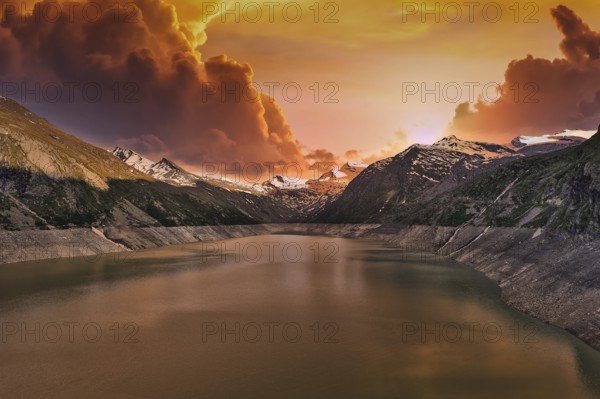 Mountain lake at sunset with dramatic clouds and orange sky, Mattmark reservoir, Saas Almagell, Saas Grund, Canton Valais, Switzerland
