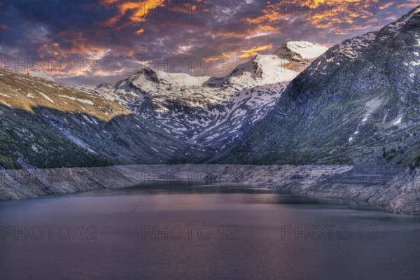 Snowy mountain peaks and a lake at sunset with pink and purple sky, Mattmark reservoir, Saas Almagell, Saas Grund, Canton Valais, Switzerland