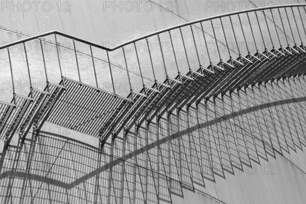 An abstract view of a metal staircase in black and white, emphasised by strong shadow lines, elevated tank, chemicals, company, Grenzach- Wyhlen, Baden-Württemberg, Germany