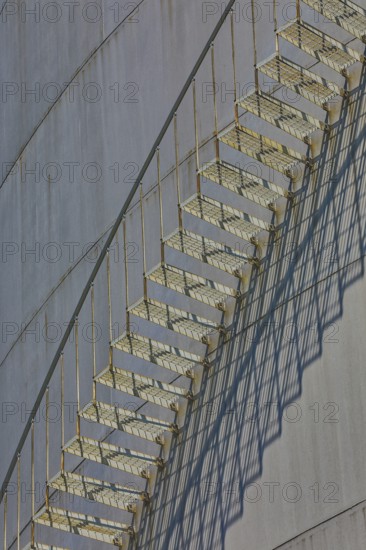 Close-up view of a metal staircase on an industrial gas tank with long shadow lines, elevated tank, chemical, company, Grenzach- Wyhlen, Baden-Württemberg, Germany