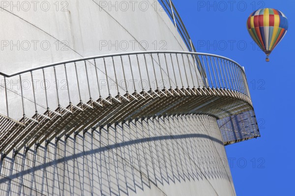 Metal staircase on a tank with a colourful hot air balloon in the sky, elevated tank, chemical, company, Grenzach- Wyhlen, Baden-Württemberg, Germany