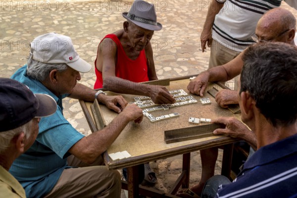 Old Cubans playing dominoes at a table on the street in the city centre of Trinidad, Trinidad, Cuba, Sancti Spíritus, Cuba, Sancti Spíritus