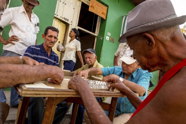 Old Cubans playing dominoes at a table on the street in the city centre of Trinidad, Trinidad, Cuba, Sancti Spíritus, Cuba, Sancti Spíritus