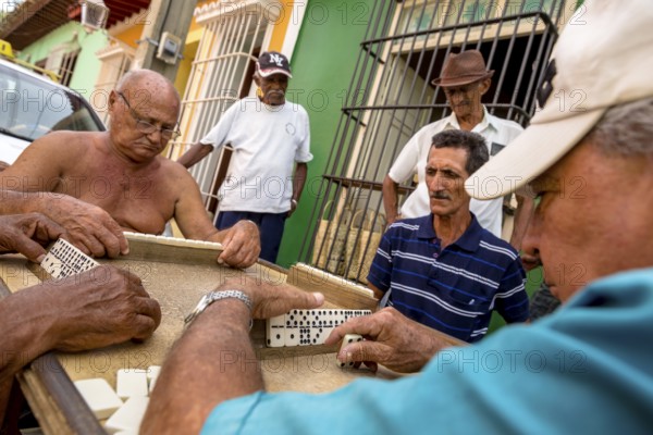 Old Cubans playing dominoes at a table on the street in the city centre of Trinidad, Trinidad, Cuba, Sancti Spíritus, Cuba, Sancti Spíritus