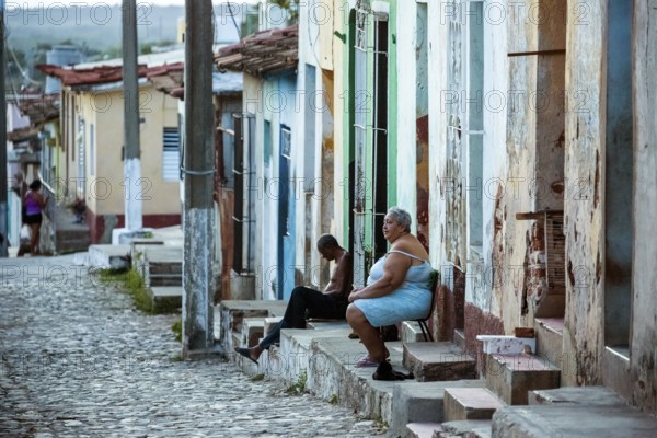 Cubans sitting on their steps in front of their houses in the old town, Street scene in the old town of Trinidad, Trinidad, Cuba, Sancti Spíritus, Cuba, Sancti Spíritus