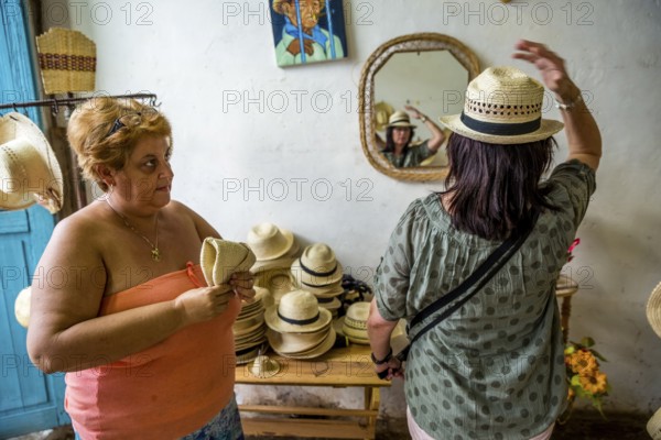 Cuban hat saleswoman with a tourist in a shop in the old town of Trinidad, Trinidad, Cuba, Sancti Spíritus, Cuba, Sancti Spíritus