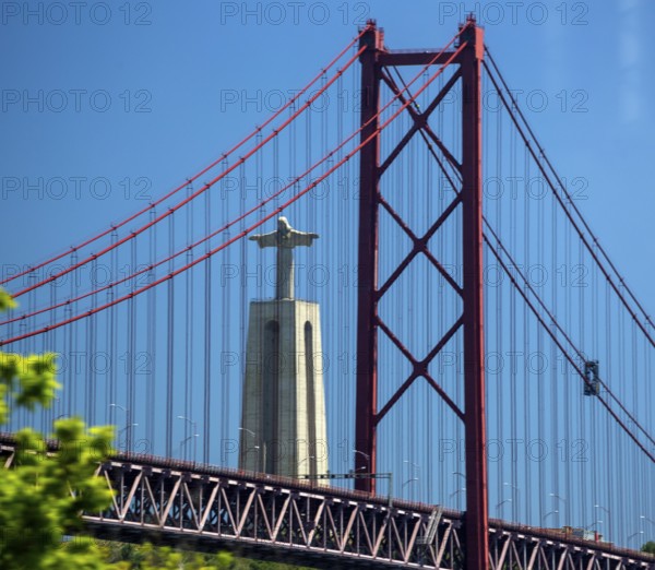The 113 metre high Cristo-Rei statue of Christ, erected in 1959, photographed through the Puente 25 de Abril bridge, Lisbon, Lisbon district, Portugal