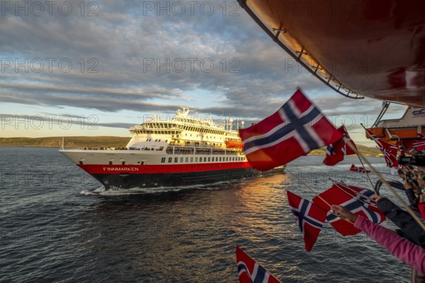 Tourists at the ship's railing, ship MS Finnmarken, Norwegian flags, Mehamn, Finnmark, Norway, Scandinavia, Europe, adventure trip, welcoming the passengers, tourism, Hurtigruten, Hurtigruten trip, cruise, cruise ship, liner, NOR, passenger ship, shipping company Hurtigruten AS, travel, destination, shipping, sea trip, sightseeing, tourism, Norwegian, Norwegian flag, Scandinavian, touristic