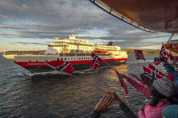 Tourists at the ship's railing, ship MS Finnmarken, Norwegian flags, Mehamn, Finnmark, Norway, Scandinavia, Europe, adventure trip, welcoming the passengers, tourism, Hurtigruten, Hurtigruten trip, cruise, cruise ship, liner, NOR, passenger ship, shipping company Hurtigruten AS, travel, destination, shipping, sea trip, sightseeing, tourism, Norwegian, Norwegian flag, Scandinavian, touristic