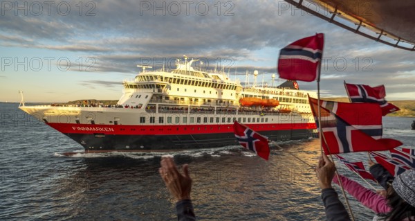 Tourists at the ship's railing, ship MS Finnmarken, Norwegian flags, Mehamn, Finnmark, Norway, Scandinavia, Europe, adventure trip, welcoming the passengers, tourism, Hurtigruten, Hurtigruten trip, cruise, cruise ship, liner, NOR, passenger ship, shipping company Hurtigruten AS, travel, destination, shipping, sea trip, sightseeing, tourism, Norwegian, Norwegian flag, Scandinavian, touristic