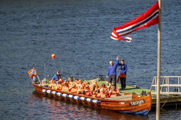 Norwegian flag, river cruise with tourists on an excursion boat, boat guide, Kirkenes, Finnmark, Norway, Scandinavia, Europe, adventure trip, excursion boat, boat trips, river boat, river cruise, tourism, Hurtigruten, Hurtigruten trip, cruise, NOR, trip, destination, sea trip, sightseeing, tourism, Trifon, Norwegian, Scandinavian, touristic